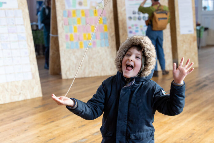 Boy laughing, balancing a stick on his hand